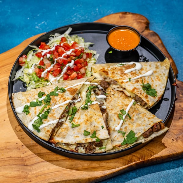 Chubby's Tacos quesadillas with meat, cheese, cilantro, and crema, served with salsa and pico de gallo.